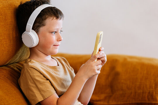 Boy sitting on a sofa using the mobile phone
