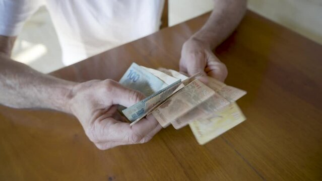 Elderly Man Counting Money. Close-up of Brazilian Real Currency.
