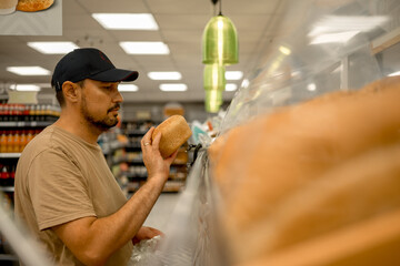 A man in a cap in a supermarket chooses fresh food. A man came to the store for shopping. Buying...