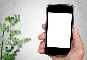 A hand hold phone against a light stone wall.