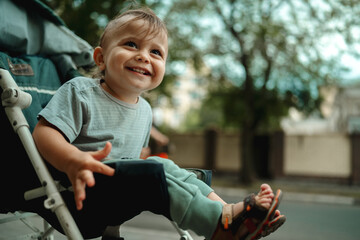 Fototapeta premium A baby is sitting in a baby carriage, a child on a walk, a portrait of a smiling cute child
