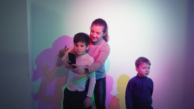 science and education, cheerful brothers pose for a photo on a smartphone background of mixed colors in a science museum for children