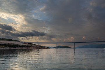 Fototapeta na wymiar Beautiful bridge across the sea to Peljesac peninsula in Croatia. There are dramatic clouds in the sky.