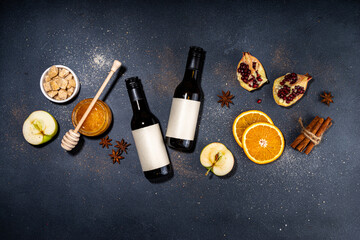 Different mulled wine ingredients set on black background, flat lay with wine bottle, cinnamon, apple, orange, anise star, simple autumn food drink cooking background