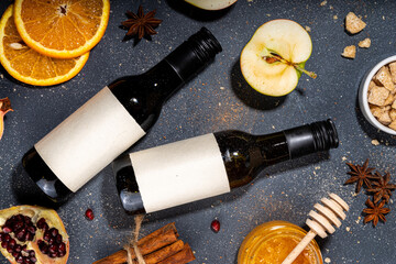 Different mulled wine ingredients set on black background, flat lay with wine bottle, cinnamon,...