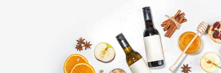 Different mulled wine ingredients set on white background, flat lay with wine bottle, cinnamon, apple, orange, anise star, simple autumn food drink cooking background