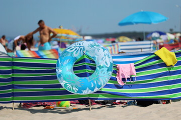 Parasol słoneczny na plaży nadmorskiej w wakacje razem z parawanem na wiatr.  - obrazy, fototapety, plakaty
