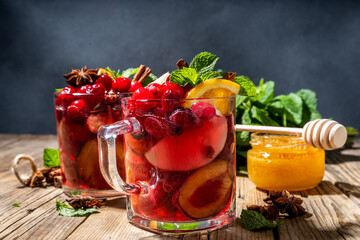 Christmas mulled wine with aromatic spices and citrus fruits and berry. Hot autumn winter fruity punch drink with red wine, on old rustic wooden background copy space 
