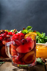 Christmas mulled wine with aromatic spices and citrus fruits and berry. Hot autumn winter fruity punch drink with red wine, on old rustic wooden background copy space 