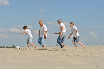 Family playing football on a beach in summer day