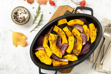 Healthy baked food. Keto, paleo diet, veggie or vegetarian meal. Roasted pumpkins slice with rosemary and purple onion on a stone tabletop. View from above.