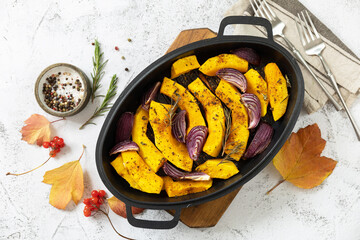 Healthy baked food. Keto, paleo diet, veggie or vegetarian meal. Roasted pumpkins slice with rosemary and purple onion on a stone tabletop. View from above.