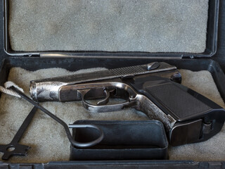 An old pistol with a set of tools (ramrod and screwdriver) lying in a box. Close-up