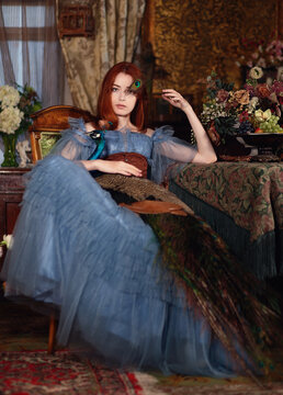 Girl in blue dress with blue peacock in her arms in room with vintage interior	
