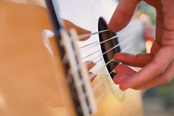 Close-up of the musician's playing hands. The guitarist plays the guitar. Professional guitarist plays guitar outdoors. Musician plays a classical guitar in the park.