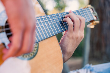 Close-up of the musician's playing hands. The guitarist plays the guitar. Professional guitarist plays guitar outdoors. Musician plays a classical guitar in the park.