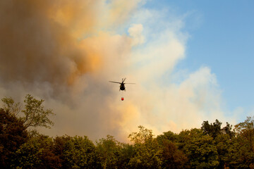 Karst, Miren-Kostanjevica, Slovenia - July 17, 2022: A large forest fire in the Karst (Kras), Slovenia. The fire surrounds the monument on Cerje hill. A military helicopters fighting a fire. - obrazy, fototapety, plakaty