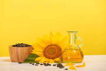 Organic sunflower oil in a small glass bottle with sunflower seeds and fresh flowers on the table. The concept of organic and environmentally friendly products. Healthy food and fats.
