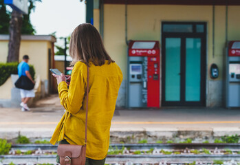 Woman with smartphone is waiting for her train.