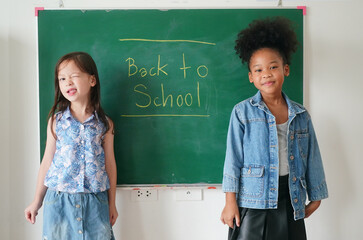 Preschool kids drawing with color pencil on white paper on table in classroom with friends, kindergarten education concept