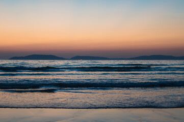 Fototapeta na wymiar sunset on the beach with mountains