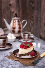 Homemade cheesecake decorated with raspberries and a retro coffee set on a gray table. Coffee still life in vintage style.