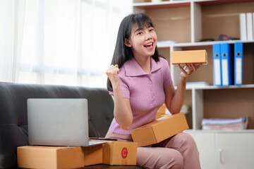 Asian small business owner woman is successful selling online using laptop computer. Happy asian business woman successful excited raised hands rejoicing.