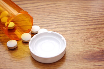 Fototapeta na wymiar Pills were poured from the orange pill bottle onto the wooden table, medicine pill on wooden table..