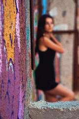 Defocused, blurred silhouette of a girl in a black dress standing near a street wall. Social problems concept. Close-up with selective focus