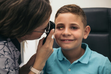 An optometrist uses an ophthalmoscope to view the back of a child's eye.