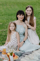 Portrait of happy mum and two daughters. Happy mother with two daughters enjoying a picnic in nature