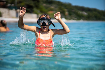 Little girl at the sea learning how to dive. She is wearing goggles. Vacation concept.