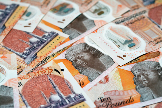 Pile of the new first Egyptian 10 LE EGP ten pounds plastic polymer banknote features Administrative capital's grand mosque Al-Fattah Al-Aleem, the pyramid and queen Hatshepsut, selective focus
