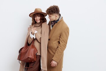 a happy couple a man and a woman are standing in stylish autumn clothes on a white background close to each other and a man looks tenderly at a woman