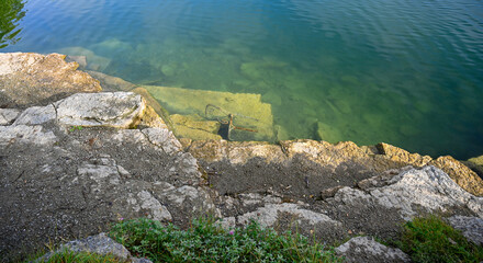 rusty metal chair lying in old quarry filled with water