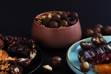 Churchkhela is a sweet delicacy of nuts in juices thickened with flour. Georgian churchkhela in a plate on a dark table with nuts. Close-up
