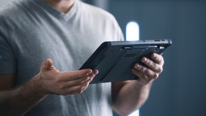 Crop male mechanic in a car service watching a car diagnostics data on a tablet and talking to client about breakdown