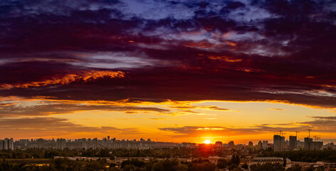Amazing panoramic view of the big city evening silhouette against the backdrop of incredibly, awesome bright, multi colored clouds at sunset. Kyiv in last days in july 2022. Ukraine.