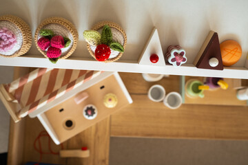 Artificial food in the children's kitchen. On the shelf are vegetables and fruits made of knitted threads