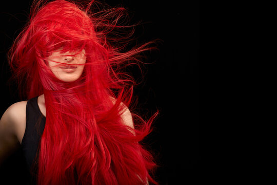 Beautiful woman with long healthy red hair. Flying hair isolated on black with copy space