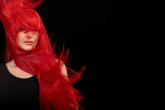 Red haired woman with a beautiful and healthy long red hair. Flying hair isolated on black