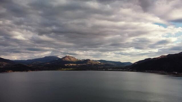 Spectacular landscape of Egirdir lake in Turkey filmed by drone from water side against mountain ridge. Aerial view of the shore with high cliffs and cloudy grey sky over it. Theme of idyllic journey.