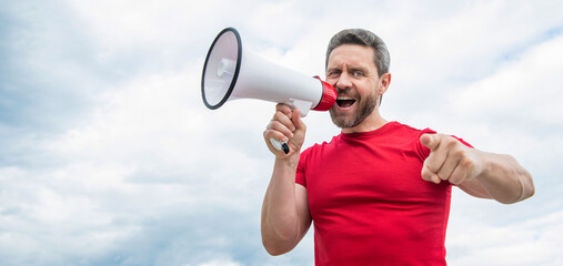 man in red shirt shout in loudspeaker on sky background. copy space