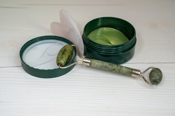 skin care accessories gua sha roller beauty tool set, jade roller next to cream eye patches, beauty...