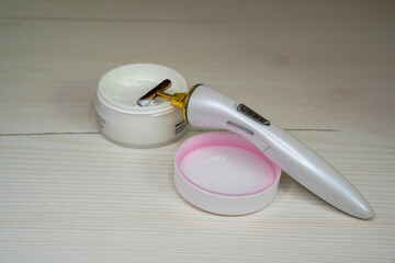 face hand massager roller next to cream jar, face care routine in salon