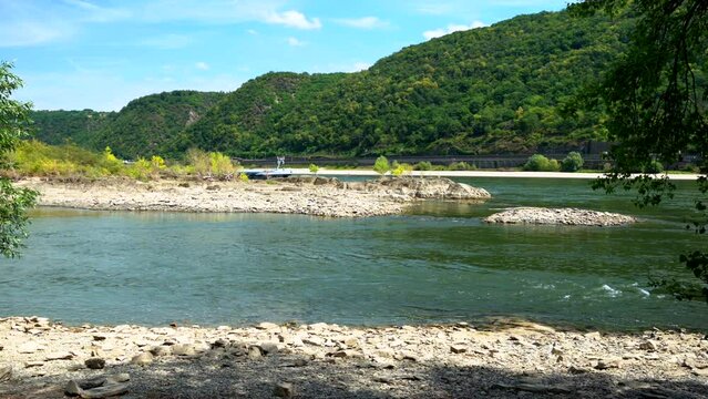 River barge passing behind the dry mud caked rocks of Rhine river during drought