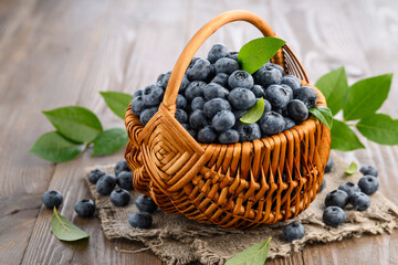 Fresh blueberries in a wicker basket on a wooden background. Farm healthy eco products. selective focus, copy space.