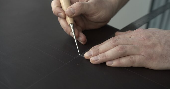 Working process of crafting a bew handmade leather wallet in the leather workshop. Concept of small business to create leather products. Horizontally framed shot.