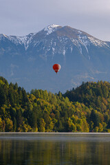 Hot air balloon floating over lake with mountains on the background. Lake Bled, Slovenia