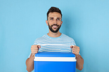Happy man with cool box on light blue background